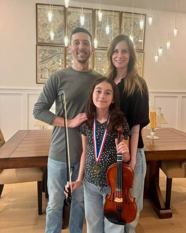 Student with a competition medal and violin, with family